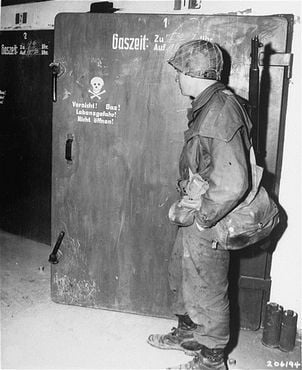 A soldier from the U.S. 7th Army examines the door to a gas chamber in the Dachau concentration .jpg