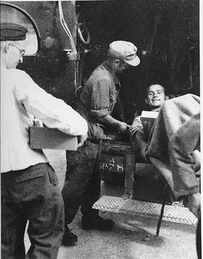 A survivor from Ebensee is loaded onto an ambulance by German military personnel for transportat.jpg