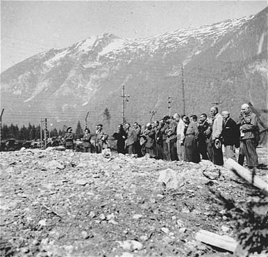 Survivors and military personnel in Ebensee attend a funeral ceremony at the edge of a mass grav.jpg