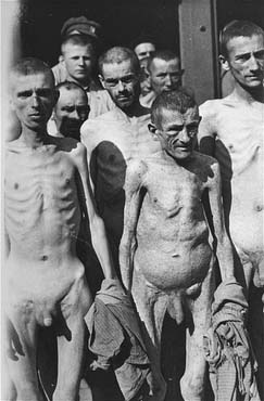 Survivors in Ebensee carrying their lice-infested clothing and blankets to a pyre for burning.jpg