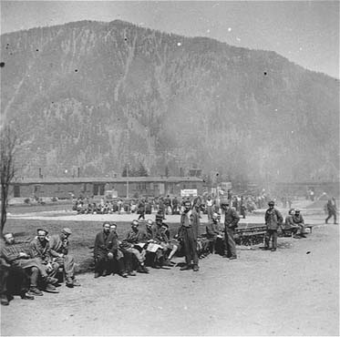Survivors sit on benches along the perimeter of the former roll call area in the Ebensee concent.jpg