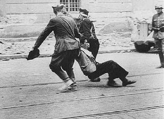 German soldier watches Ukrainian civilians drag a Jew down a street in Lvov.jpg