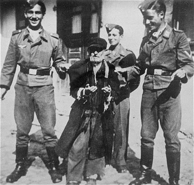 Three young Germans publicly humiliate an elderly Jew in the streets of Krzemieniec.jpg
