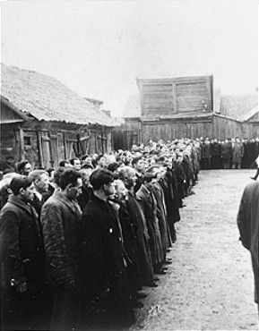 Jewish men are lined up in a large courtyard or public square in Raciaz.jpg