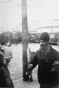 A Jewish man walks along the sidewalk near the town square in Raciaz.jpg