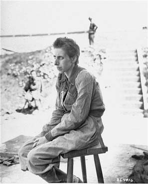 A female survivor poses outside sitting on a stool in the newly liberated.jpg
