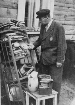 A Jew looks through discarded books piled outside a house in the Kovno ghetto.jpg