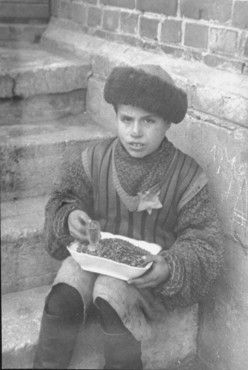 A young boy sitting on stairs outside, selling sunflower seeds.jpg