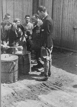 Prisoner forced laborers crowd around containers of food..jpg