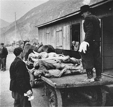 Austrian civilians stack the bodies of Ebensee prisoners onto carts for transportation to a near.jpg