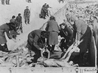 A British soldier watches women SS guards who were forced to carry victims' corpses to mass grav.jpg