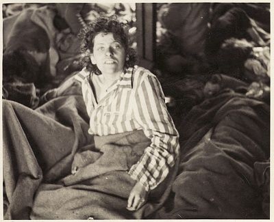 female-survivor-other-women-lie-covered-blankets-floor-barracks.jpg