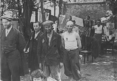 group-jewish-men-stand-among-furniture-hanging-laundry-kutno-ghetto.jpg