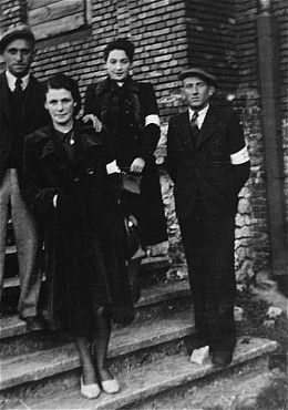 Four young Jewish men and women pose wearing armbands on a staircase in the Olkusz ghetto.jpg