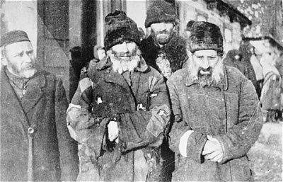 four-jewish-men-wearing-tattered-overcoats-pose-street-wisznice-ghetto.jpg