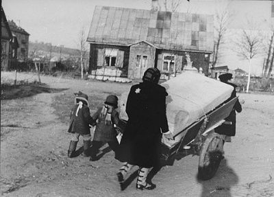 woman-pushes-cart-piled-household-belongings-through-streets-kovno-ghetto.jpg