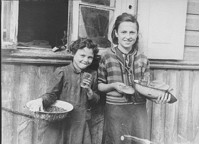 two-young-girls-stand-outside-house-kovno-ghetto-holding-bread-bowls-food.jpg