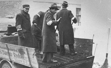 Kraków Ghetto in Podgórze: Life, Deportations and Liquidation, 1941-1943 - A group of Jewish men wearing armbands, shovel coal off the back of a truck