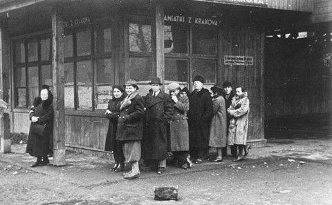 Kraków Ghetto in Podgórze: Life, Deportations and Liquidation, 1941-1943 - Jews wait in line on a street corner in the Krakow ghetto The sign in Polish reads, Souvenirs f