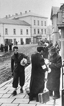 Two Jewish men examine lighting fixtures on the street in the Krakow ghetto.jpg