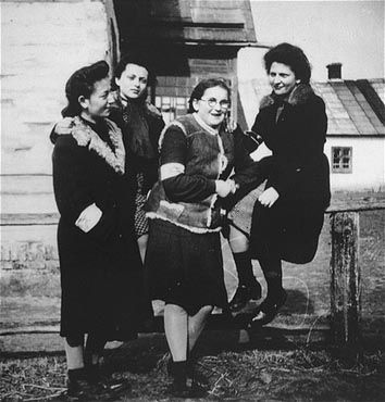 Kolbuszowa and Rzeszów Jewish Life and Ghetto Photos, 1929-1941 - Four young women wearing armbands pose next to a fence in the Kolbuszowa ghetto