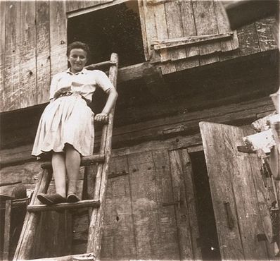 Pepka Weitz, a friend of Naftali Saleschütz, poses on a ladder in front of a wooden building in .jpg