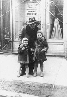 A Jewish man poses with his two nieces on a street in Rzeszow, Poland.jpg