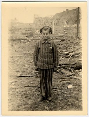 child-survivor-uniform-stands-smiling-amid-rubble-nordhausen-concentration-camp.jpg